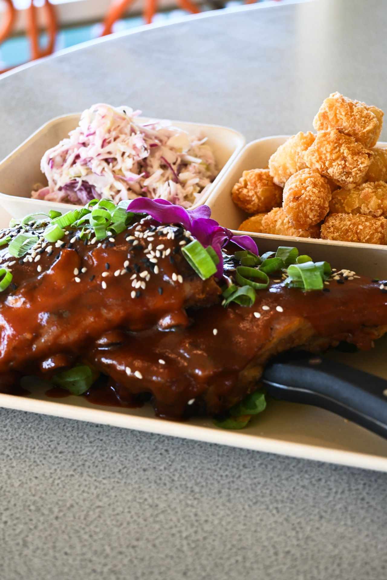 Glazed barbecue ribs with sesame and green onion, slaw and tater tots