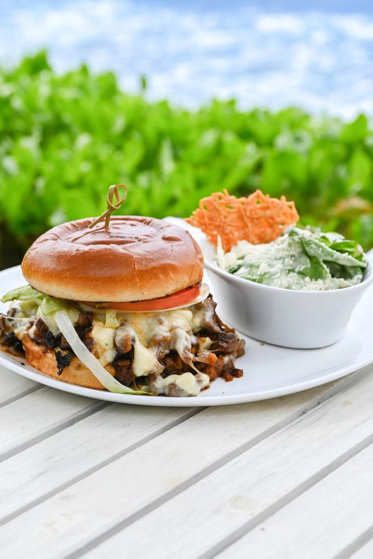 Cheesy shredded beef sandwich with a Caesar salad and crisp parmesan tuile by the water