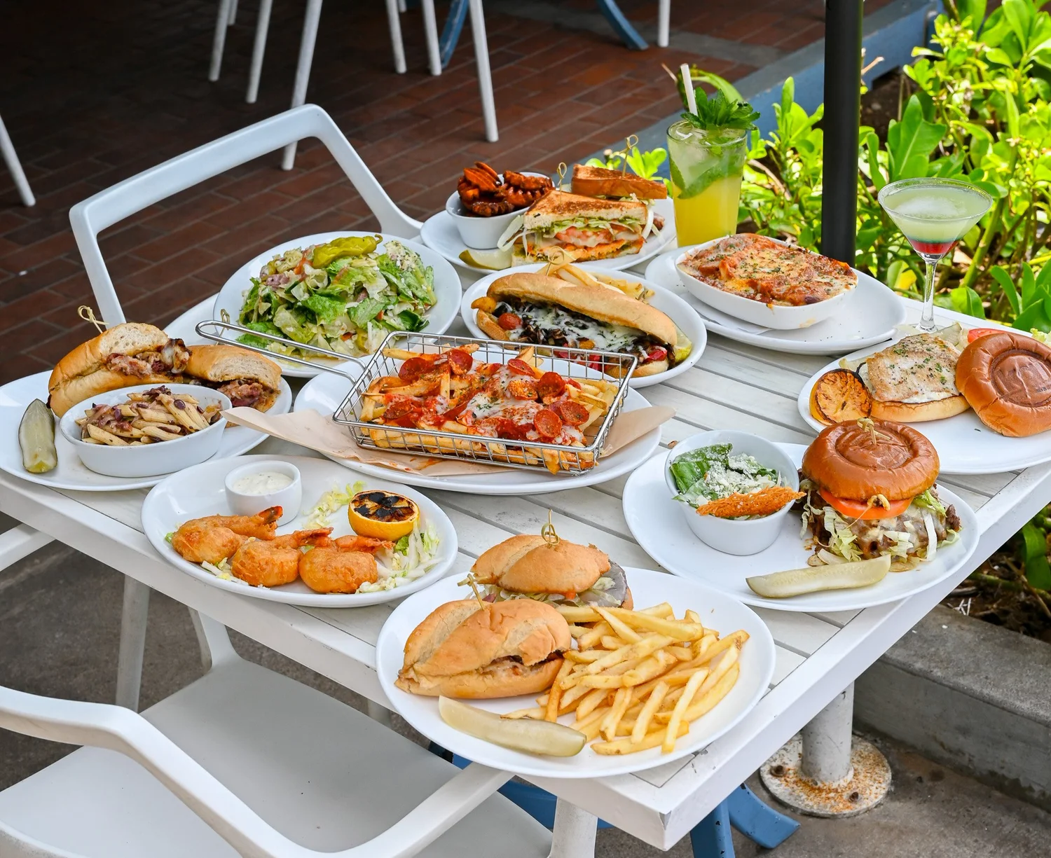 Oceanfront table spread with pepperoni fries, sandwiches, burgers, salads and cocktails