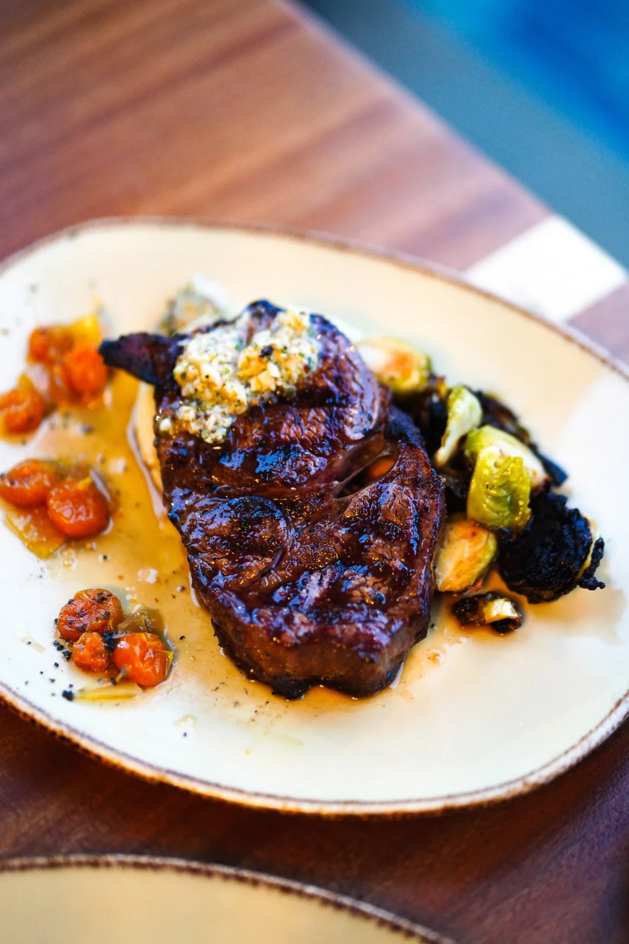Grilled steak with herb butter, blistered tomatoes and charred Brussels sprouts